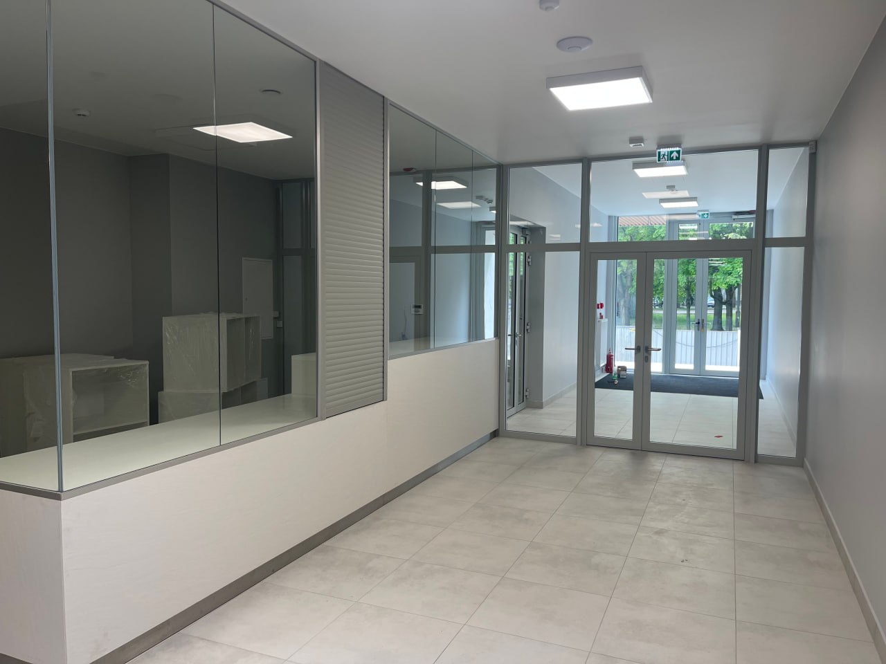Aluminiowe drzwi i ścianki szklane w nowoczesnym budynku biurowym z jasnym holem wejściowym